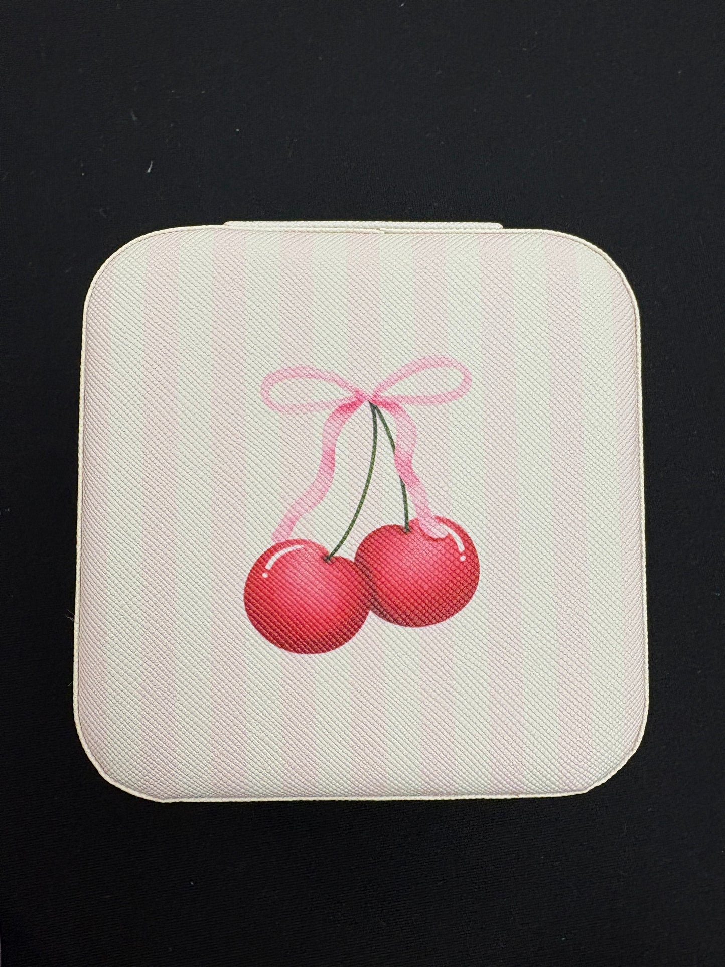 Square white jewelry box with red cherries design on a black background