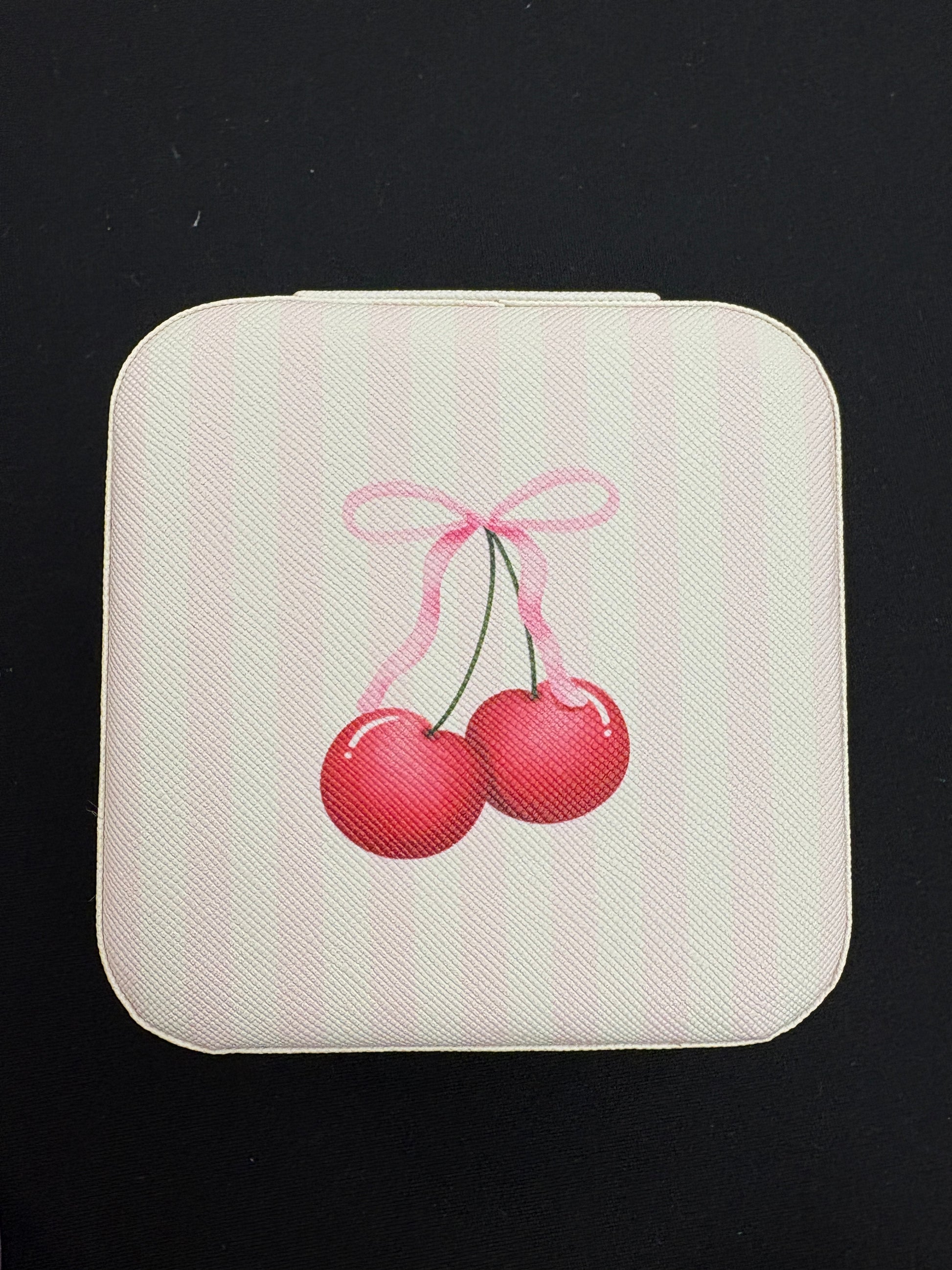 Square white jewelry box with red cherries design on a black background