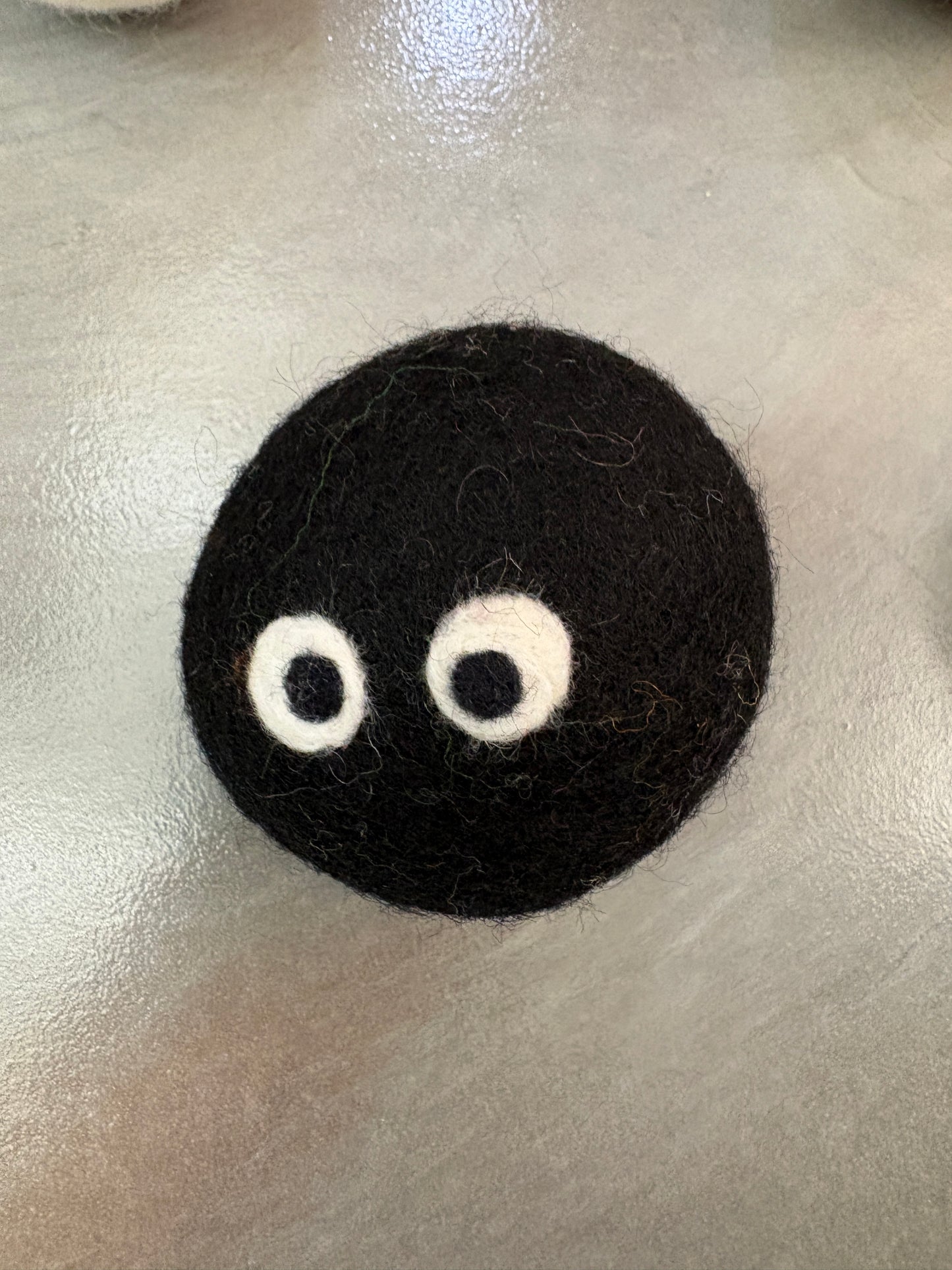 Black and white eye balls on black wool dryer ball  on gray surface