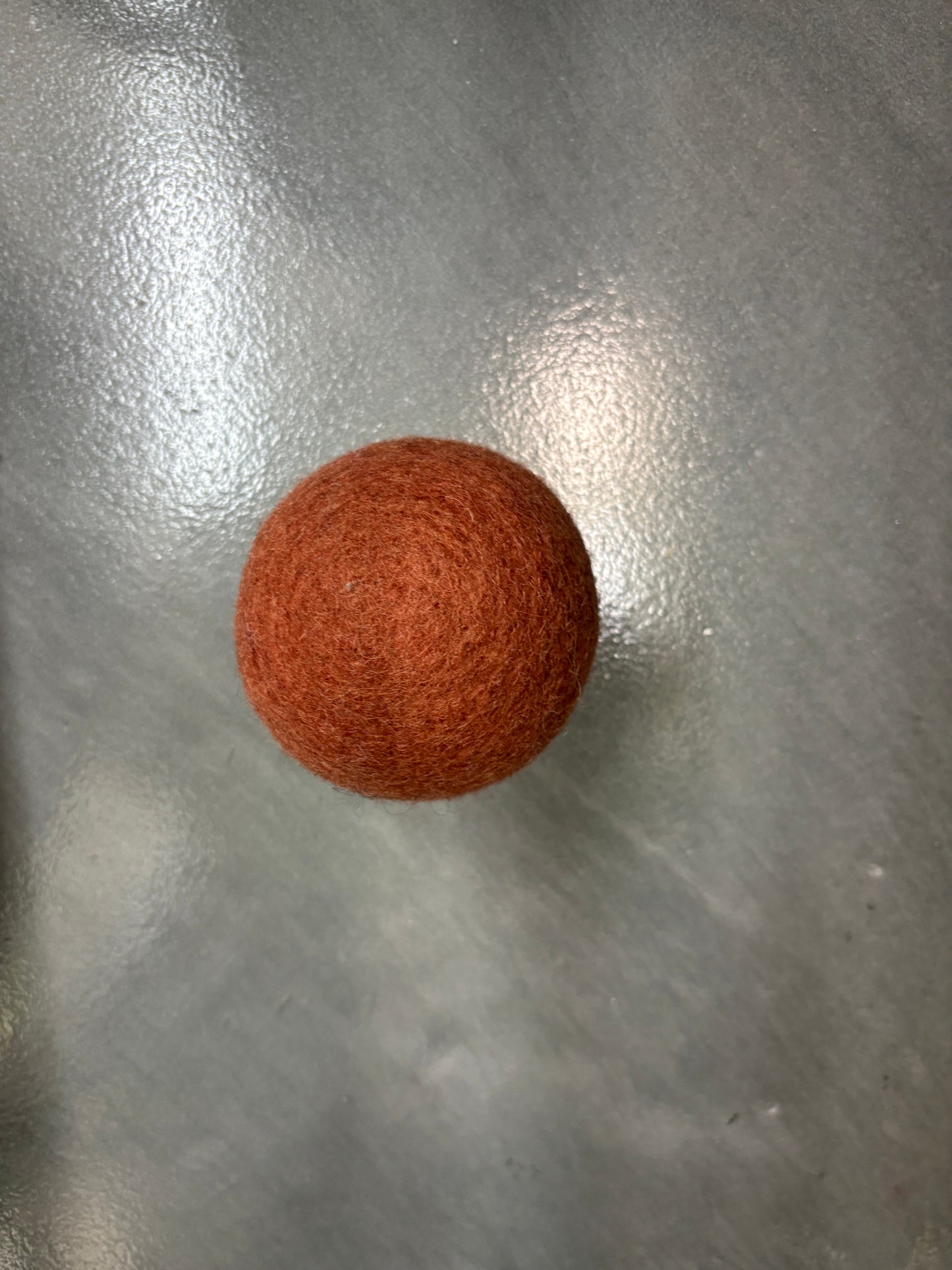Brown wool dryer ball on a metallic surface