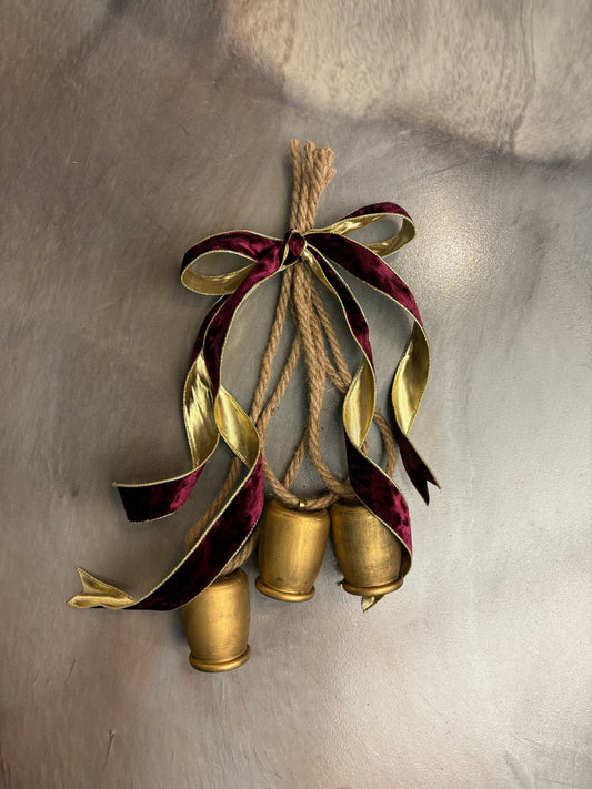 Brass bells on twine rope with burgundy ribbon on gray background