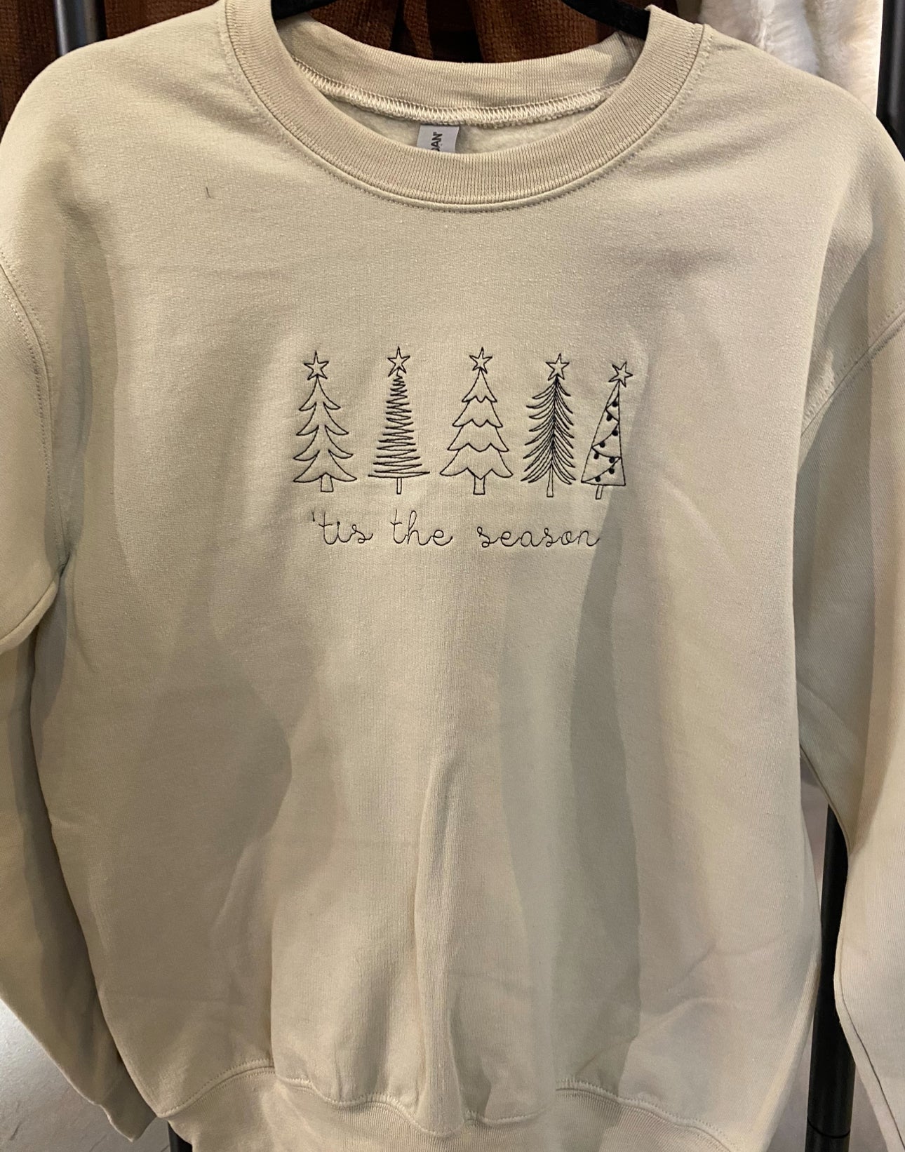 Cream colored crewneck sweatshirt with trees embroidered on it