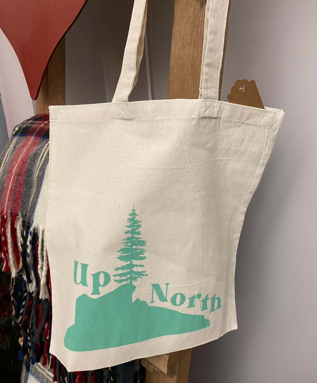 Up north canvas tote bag hanging up on white background