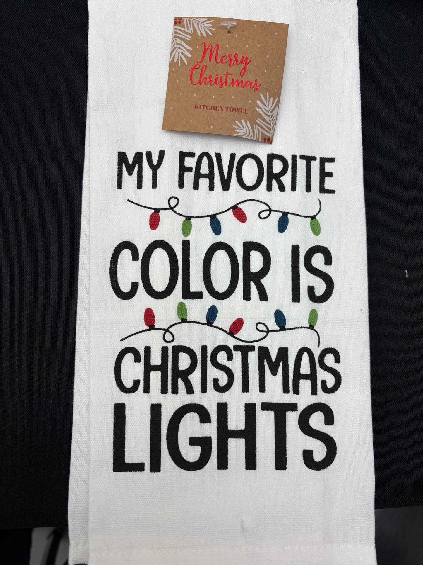 Towel with text 'My favorite color is Christmas lights' and a small gift card attached.