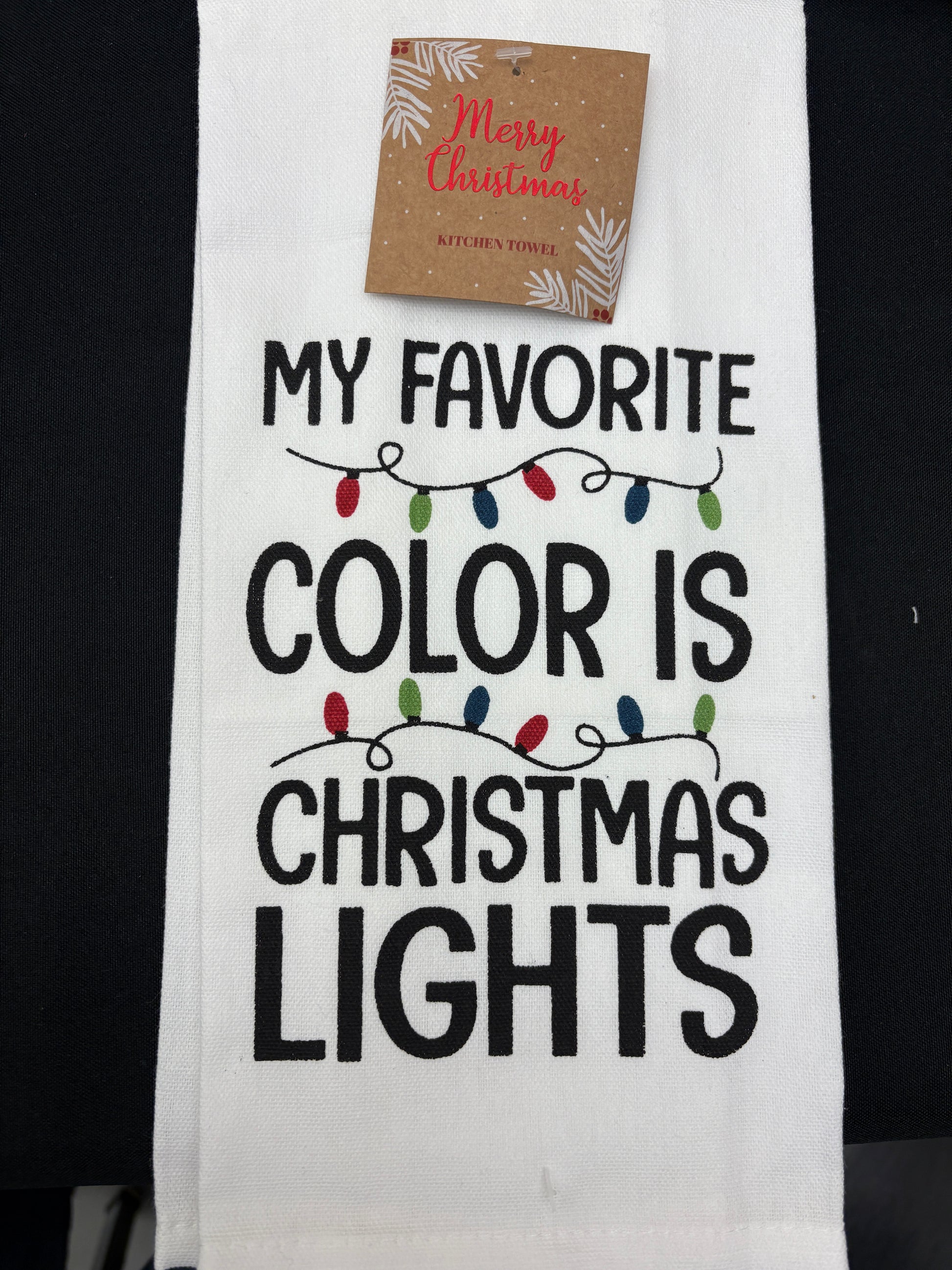 Towel with text 'My favorite color is Christmas lights' and a small gift card attached.