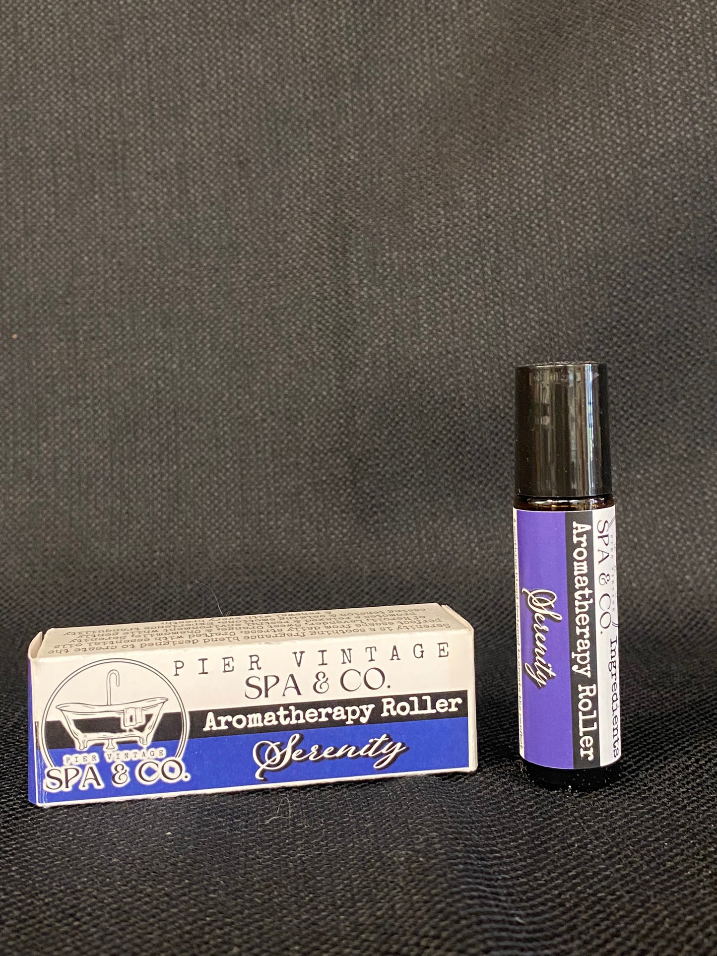Aromatherapy roller and its packaging on a dark surface