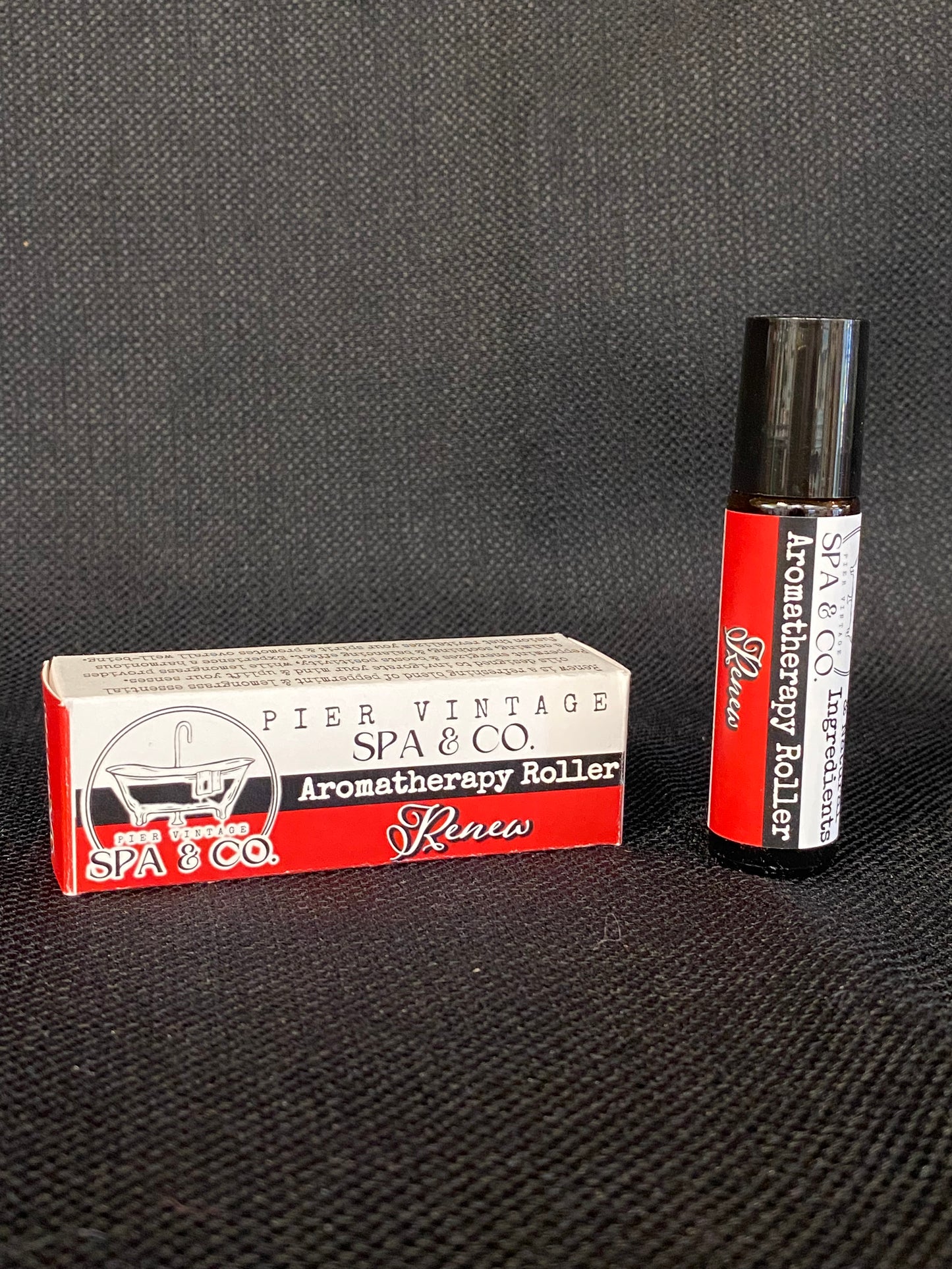 Aromatherapy roller pen and its packaging on a textured black surface