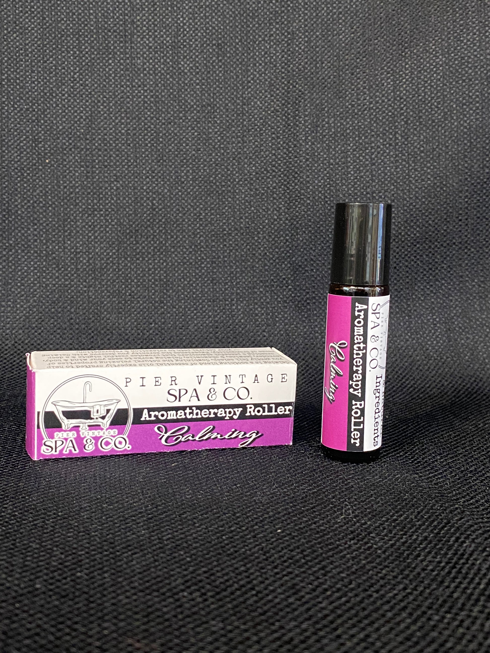 Aromatherapy roller ball with packaging on a dark textured surface