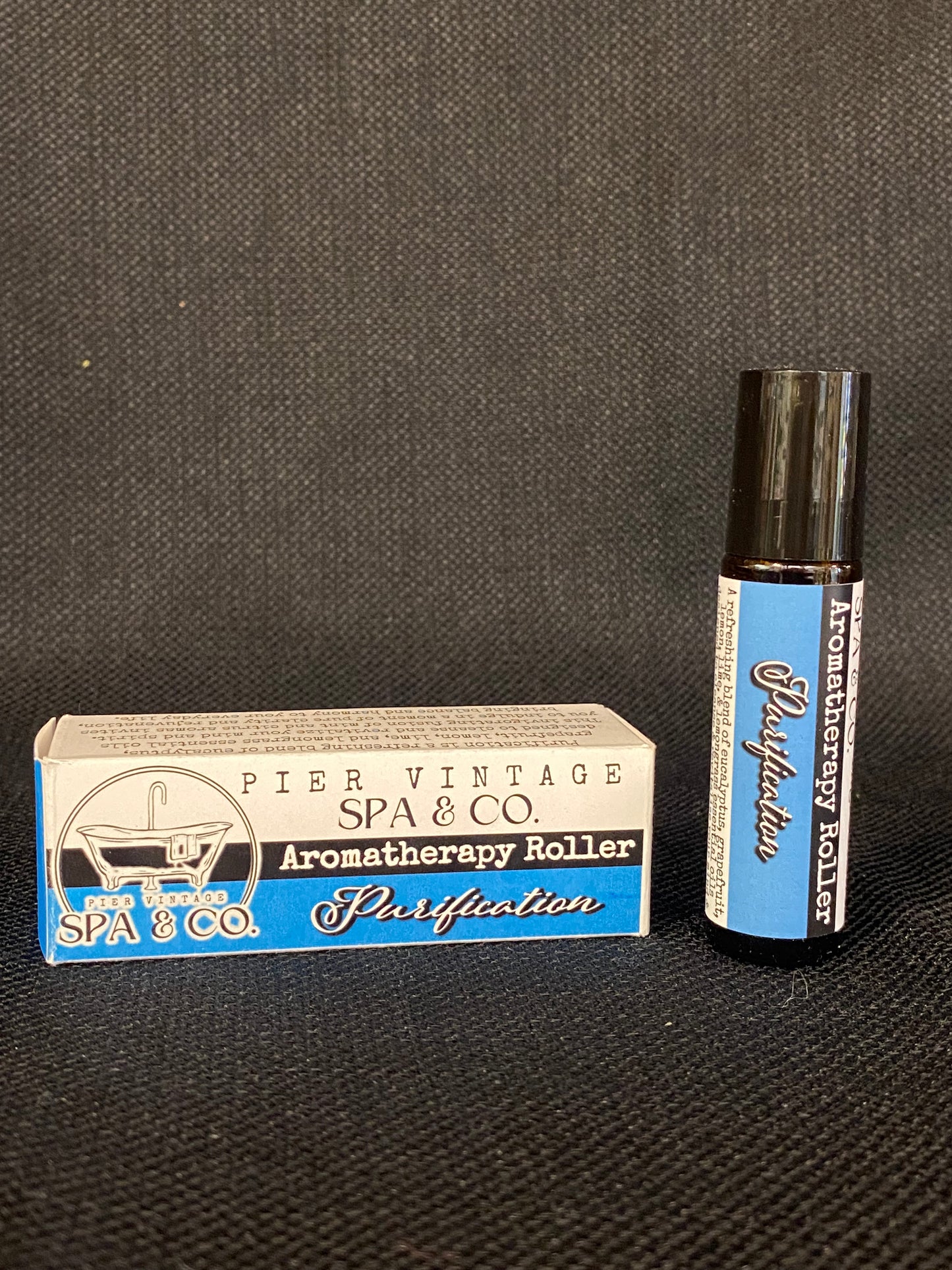 Aromatherapy roller and packaging on a dark textured surface