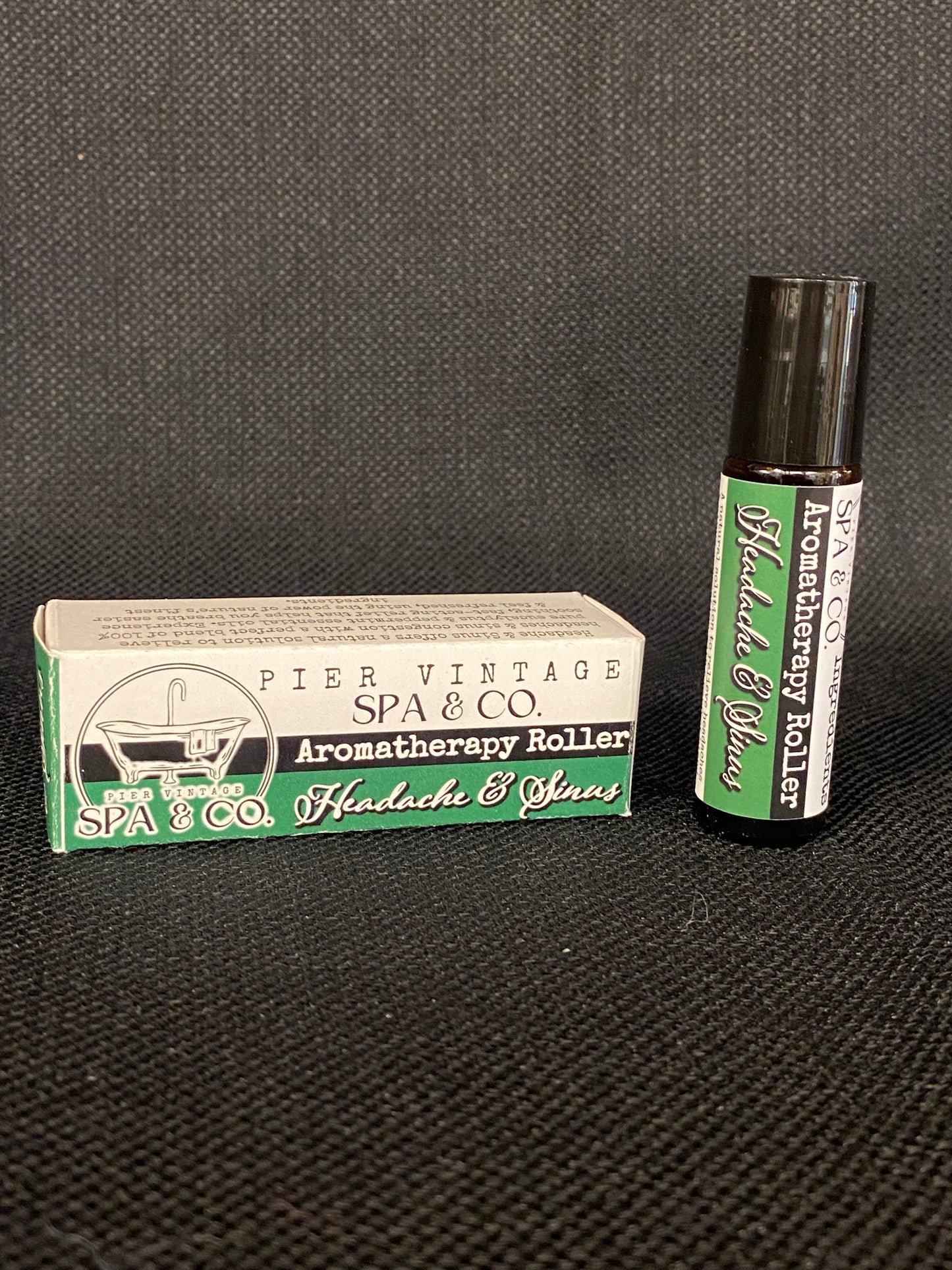 Aromatherapy roller and packaging on a textured black surface