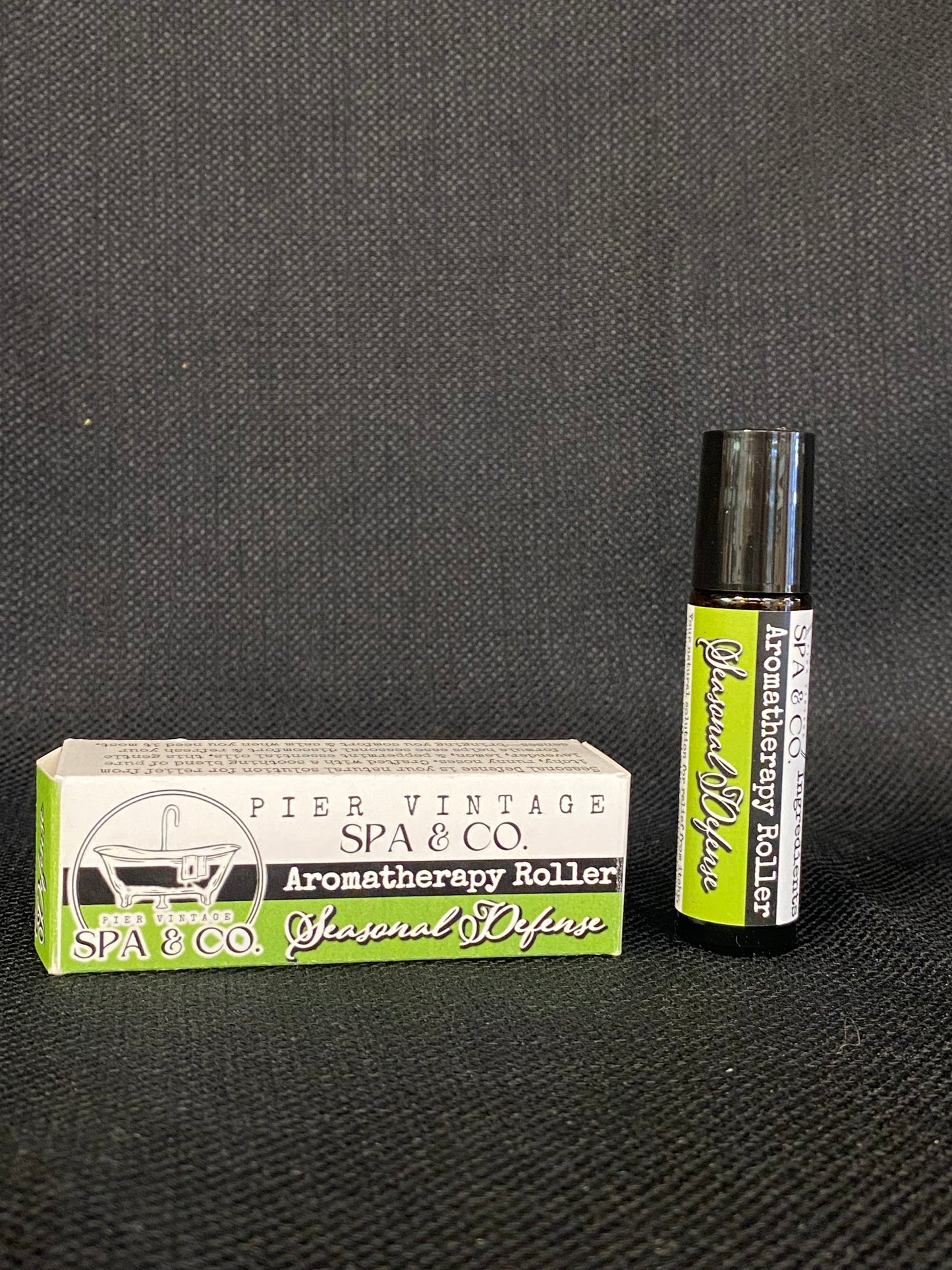 Aromatherapy roller and packaging on a dark textured surface