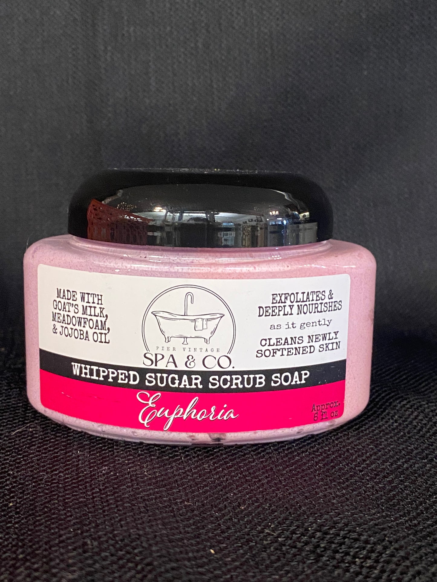 Jar of whipped sugar scrub soap with a pink and white label on a textured black surface from Pier Vintage Spa & Co.