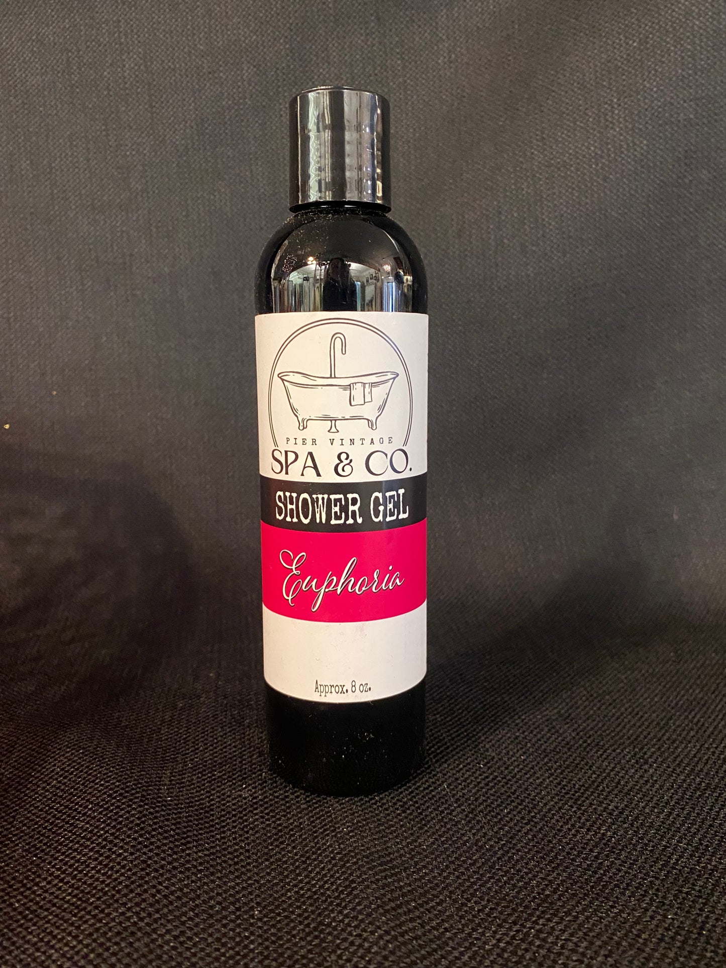 Bottle of Euphoria shower gel with a label on a dark textured surface by Pier Vintage Spa & Co.