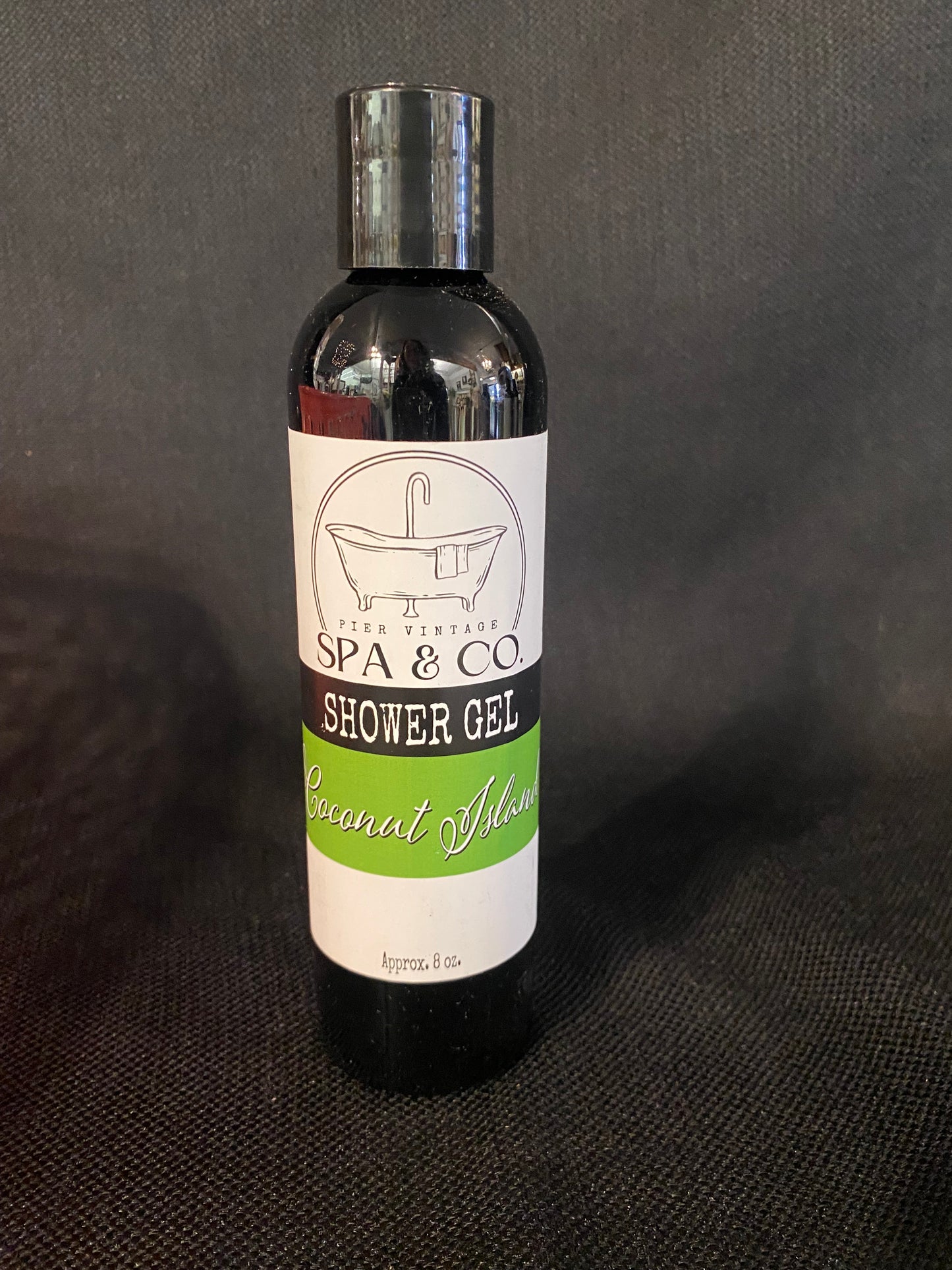 Bottle of Coconut Island shower gel with a label on a dark textured background by Pier Vintage Spa & Co.