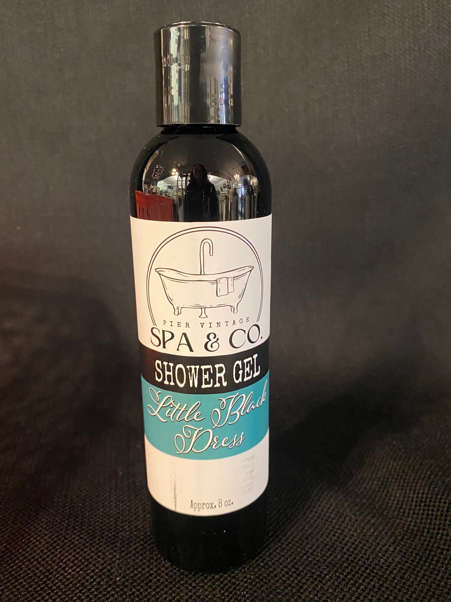 Bottle of Little Black Dress shower gel with a label on a dark textured background by Pier Vintage Spa & Co.