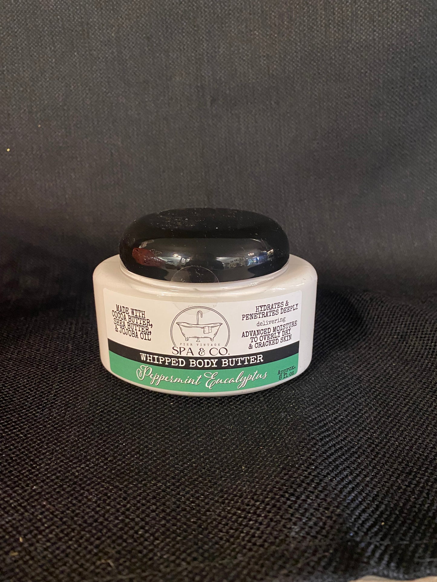 Container of Whipped Body Butter called Peppermint & Eucalyptus by Pier Vintage Spa & Co. on a dark textured surface