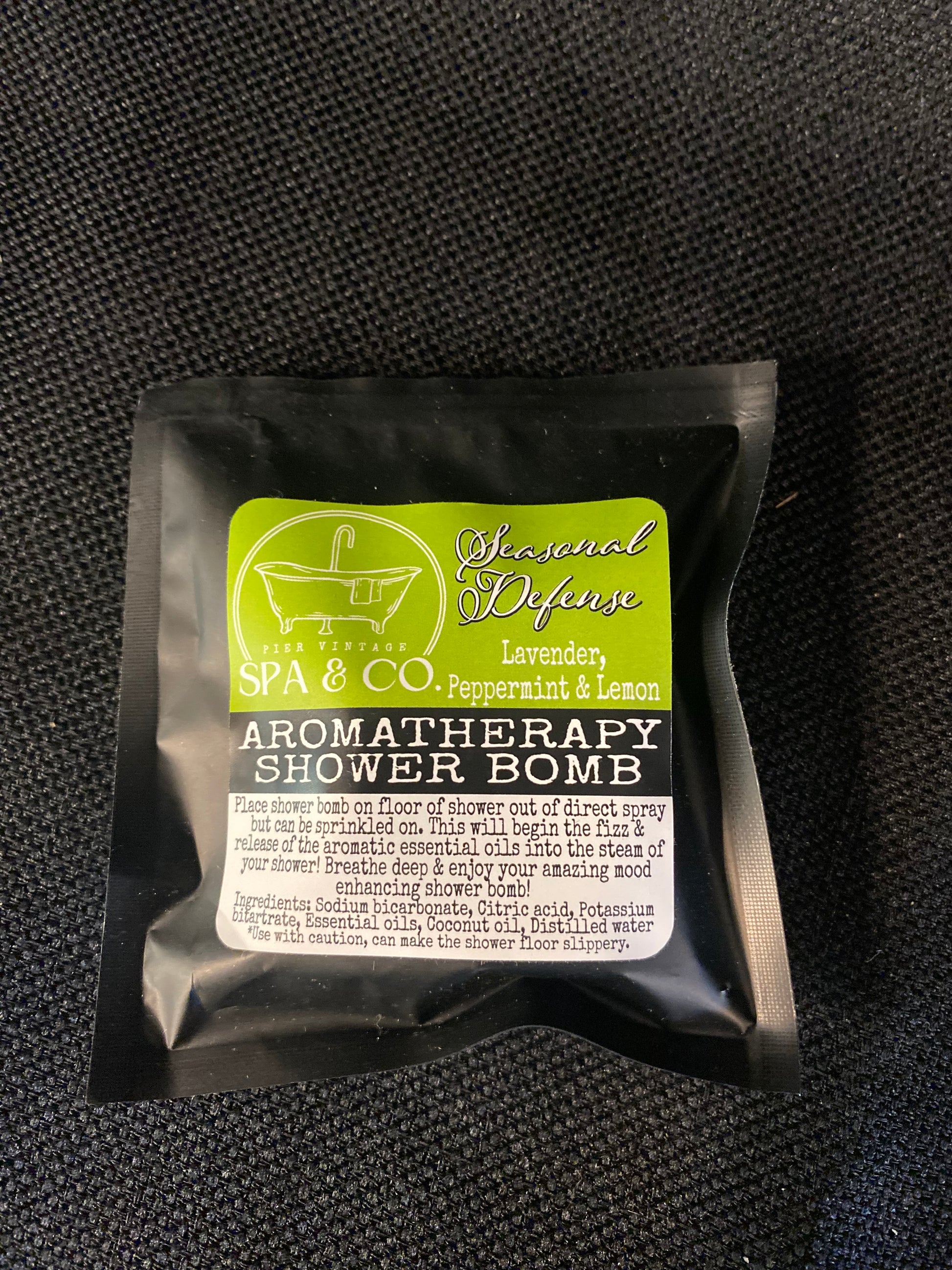 Aromatherapy shower bomb packaging on a black textured background