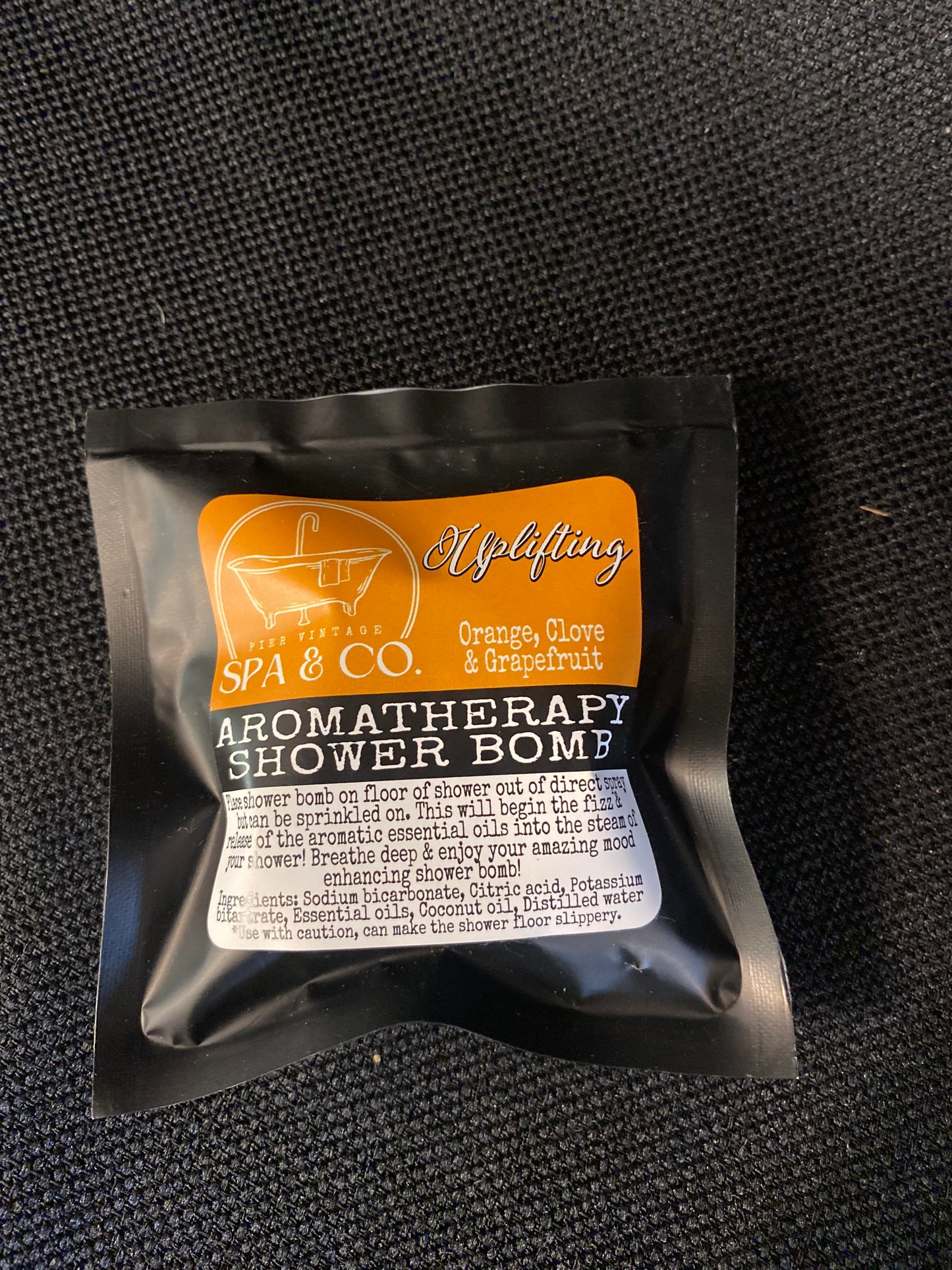 Aromatherapy shower bomb packaging on a textured black surface
