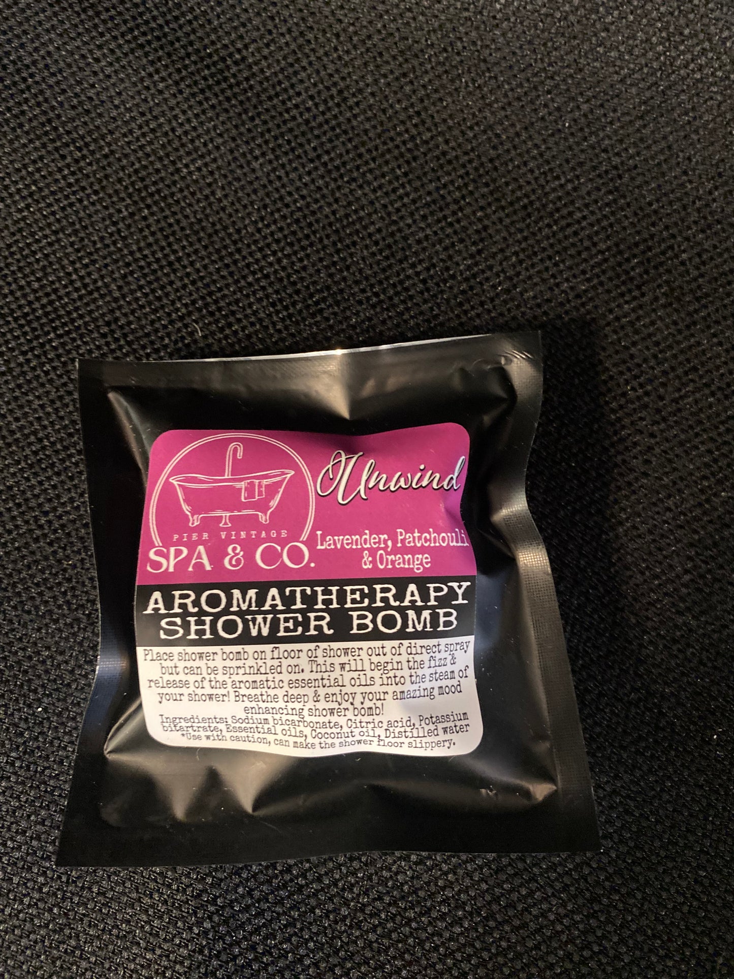 Aromatherapy shower bomb packaging on a black textured background
