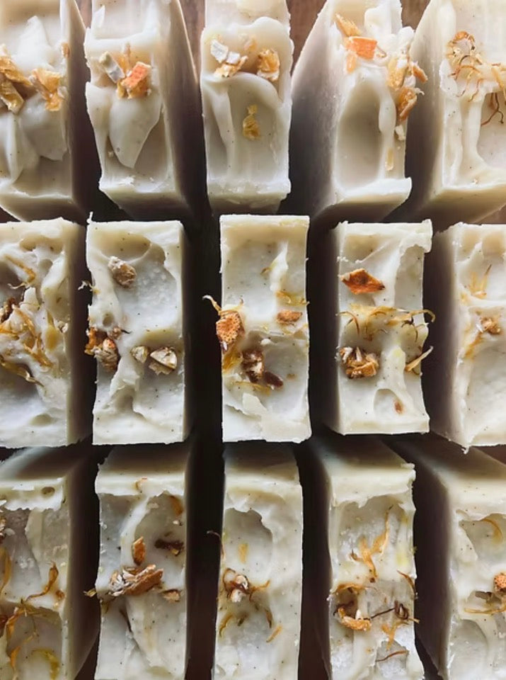 Close-up of white soap bars with dried flowers on a grid background