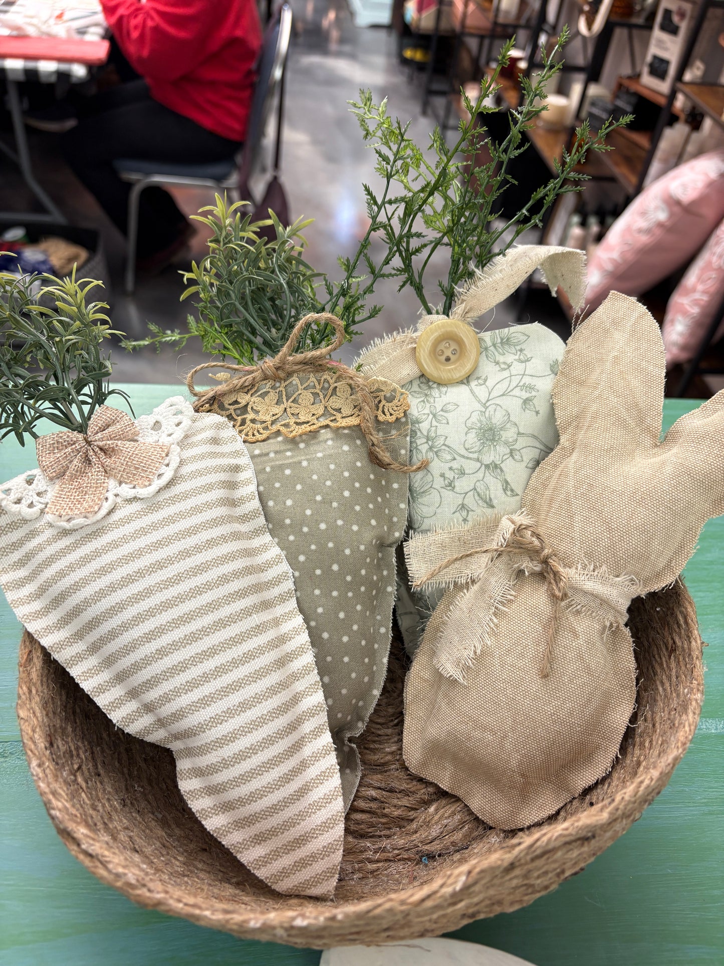 Decorative bunny with greenery and fabric in a woven basket on a blurred background