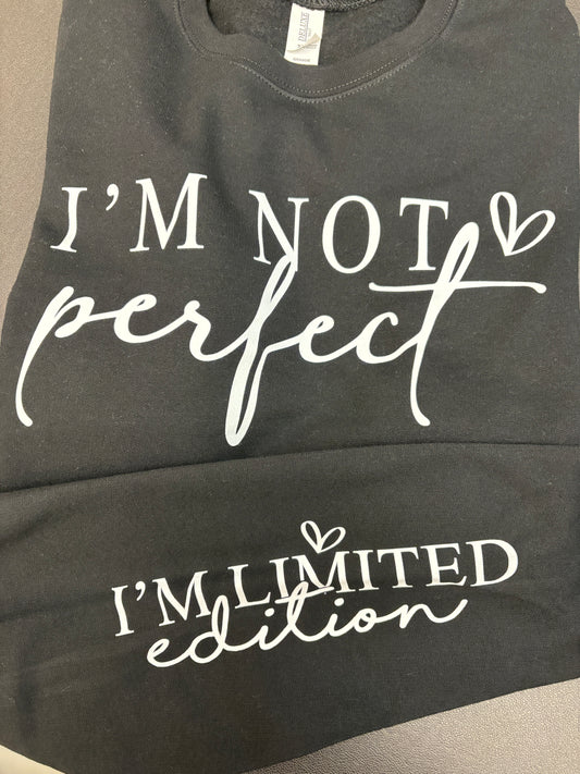 Black crewneck sweatshirt with white text on a gray surface that states I'm not perfect I'm limited edition
