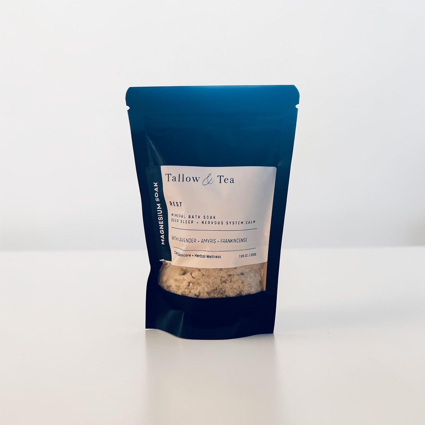 Black package of Tallow & Tea Mineral bath soak with a white label on a white background