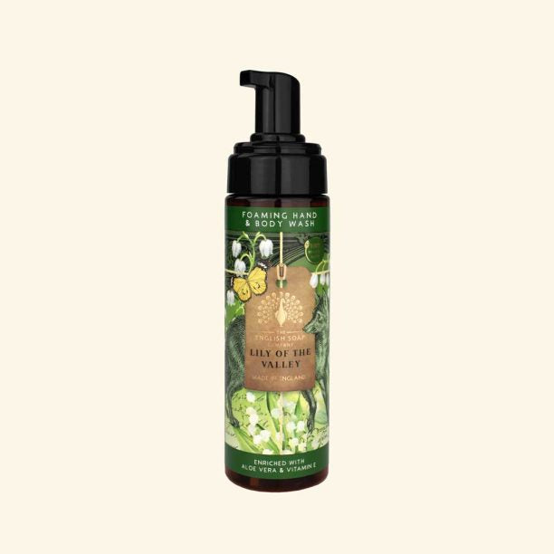 Foaming hand and body wash bottle with green label on a beige background