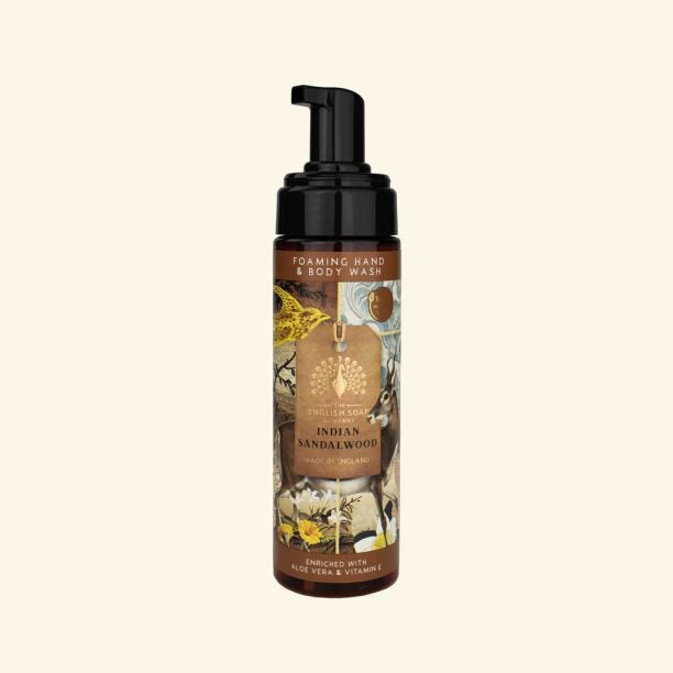 Foaming hand and body wash bottle with a decorative label on a beige background