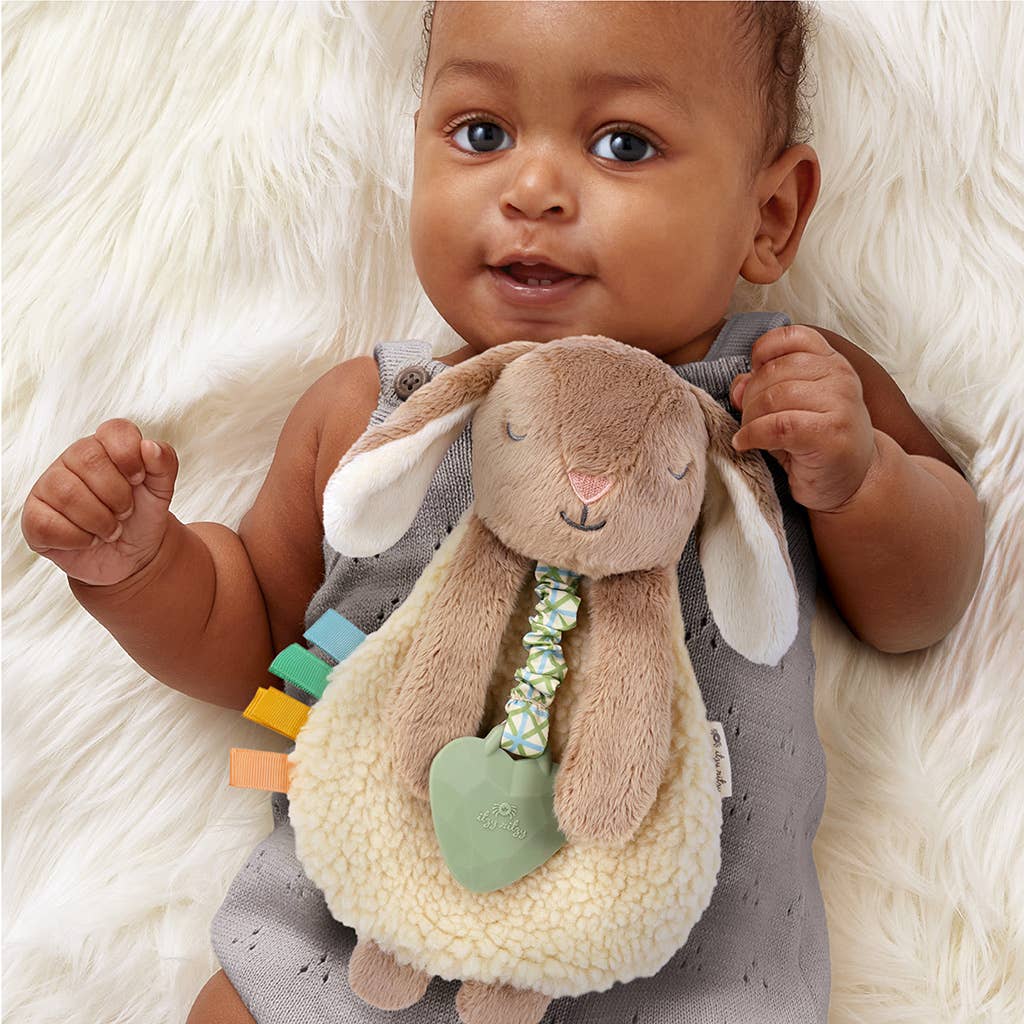 Baby holding a plush toy with colorful elements on a soft white background