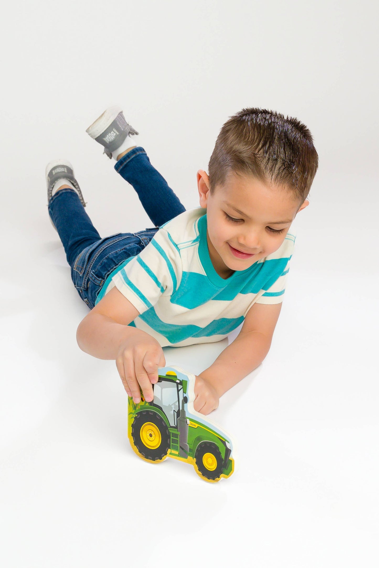 Child playing with a toy tractor book on a white background