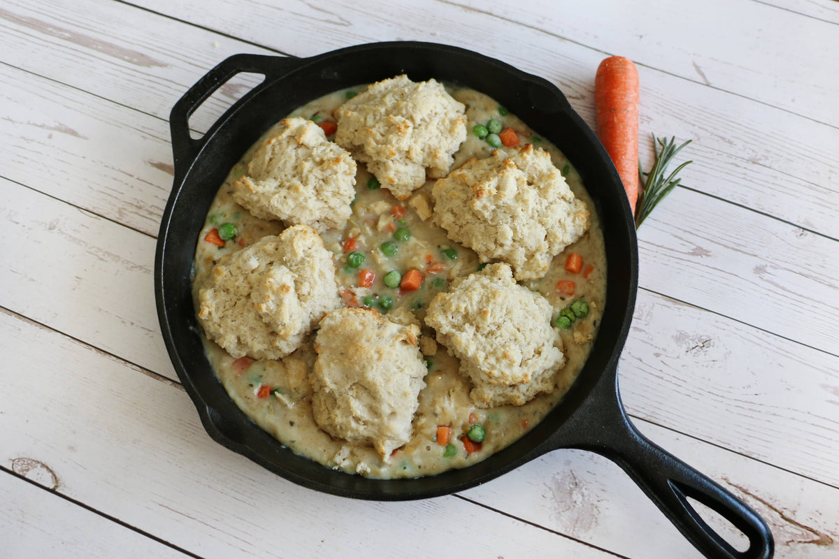 Skillet with chicken and dumplings on a wooden surface