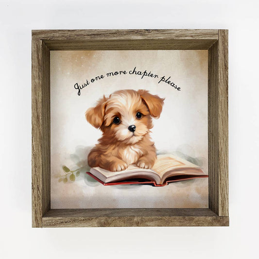 Framed artwork of a puppy with a book and text 'Just one more chapter please' on a light background.
