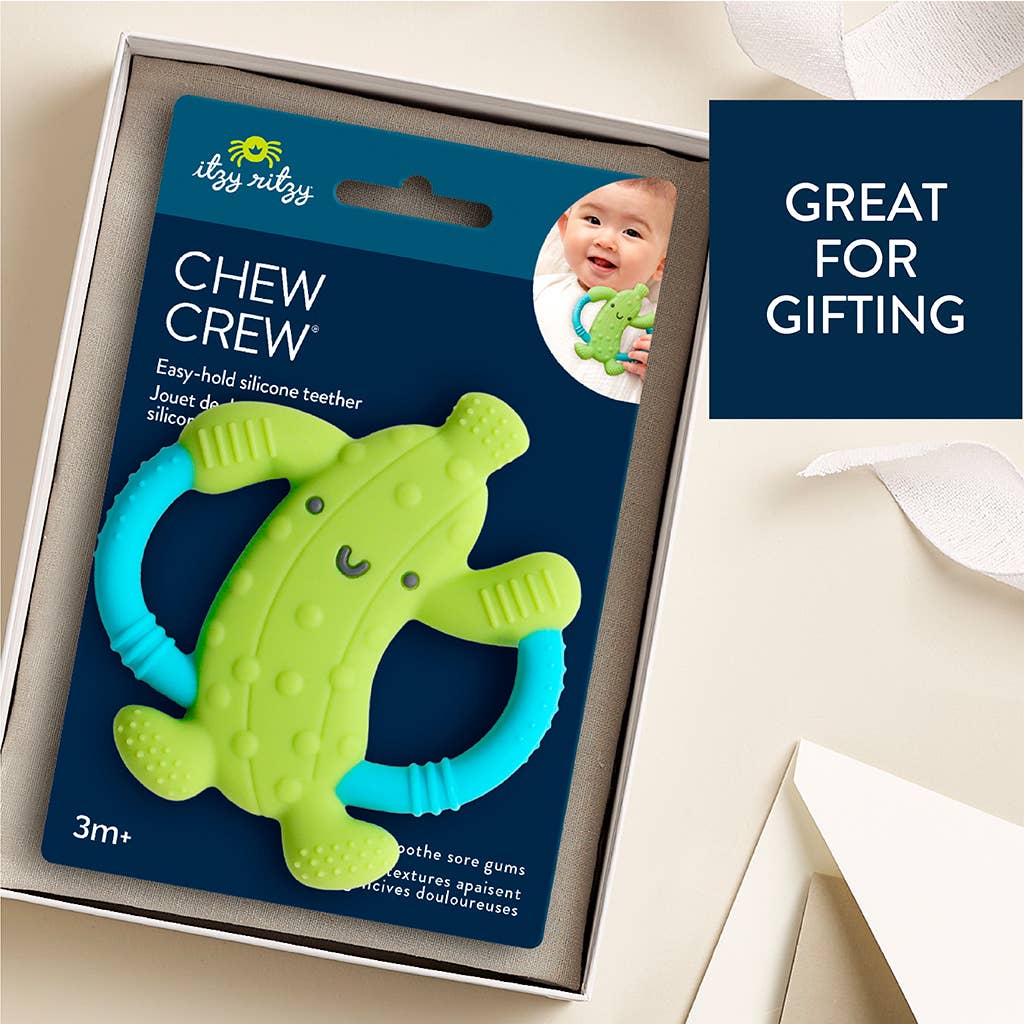 Green and blue silicone teether with packaging labeled 'Chew Crew' on a beige background.
