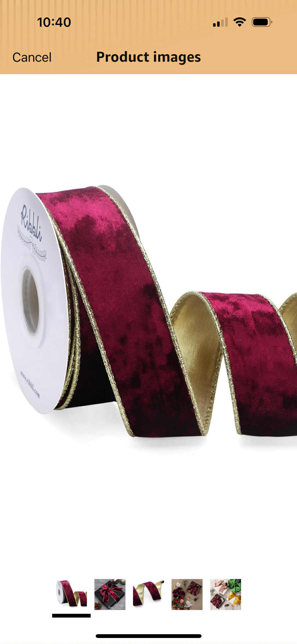 Roll of burgundy ribbon with a white core on a white background