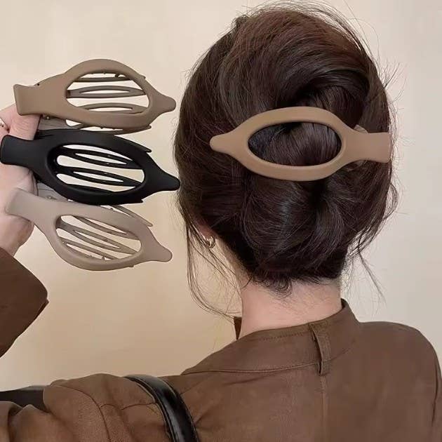 Person styling hair with a hair bun maker on a beige background
