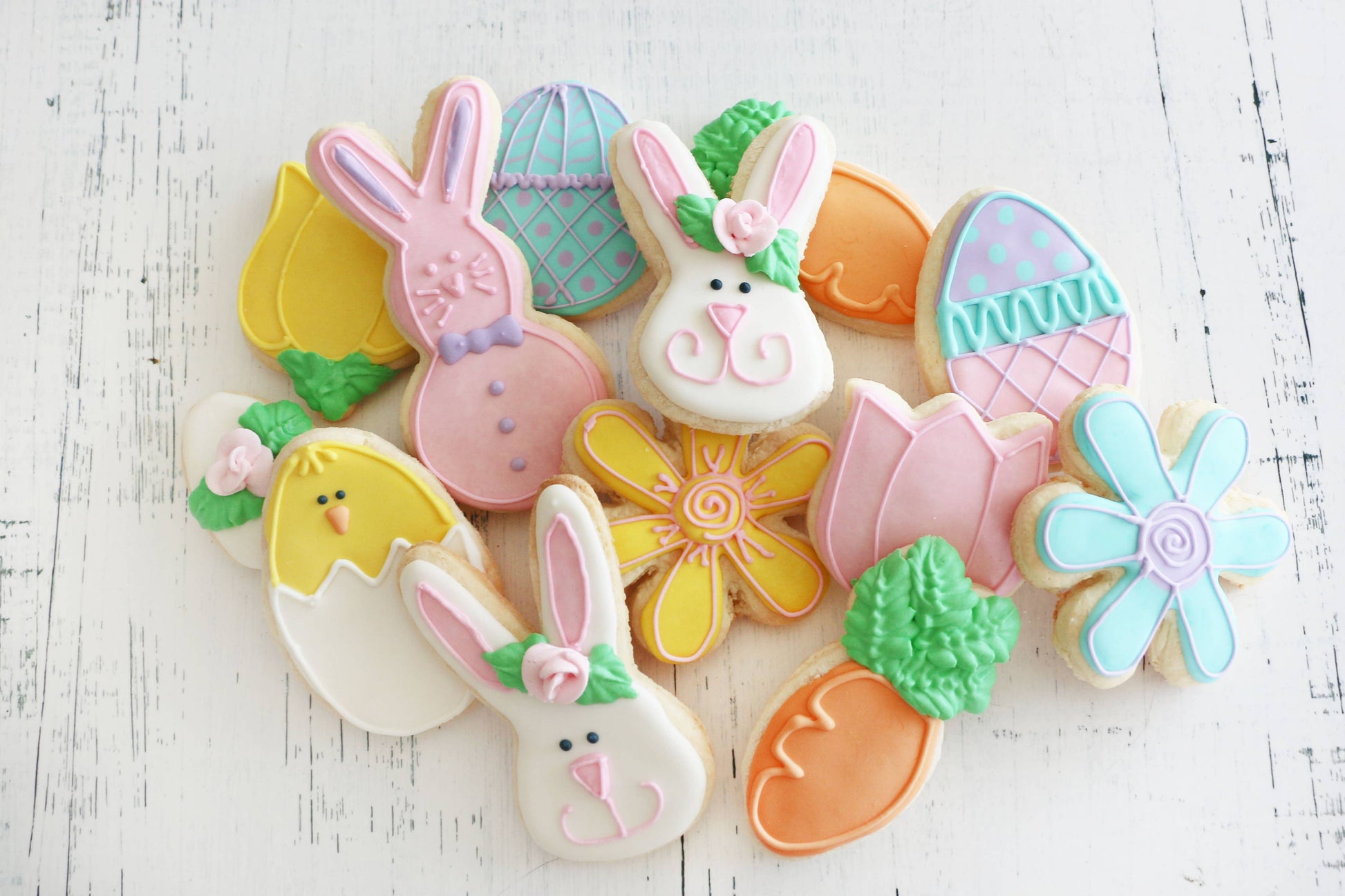 Decorative cookies shaped like bunnies, eggs, and flowers on a white wooden surface
