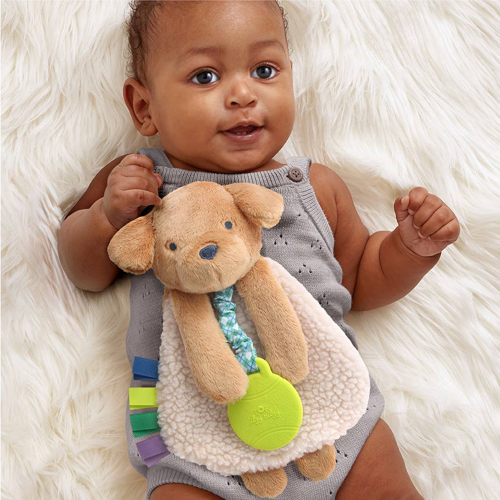 Baby holding a soft toy with colorful accents on a fluffy white surface