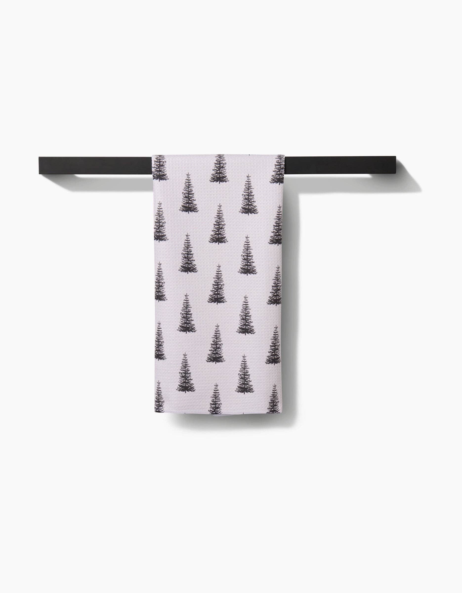 Geometry Tea Towel Alpine Forest Towel with tree pattern hanging on a black rack against a white background