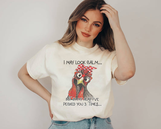 Woman wearing a white t-shirt with a rooster graphic and text, against a plain background