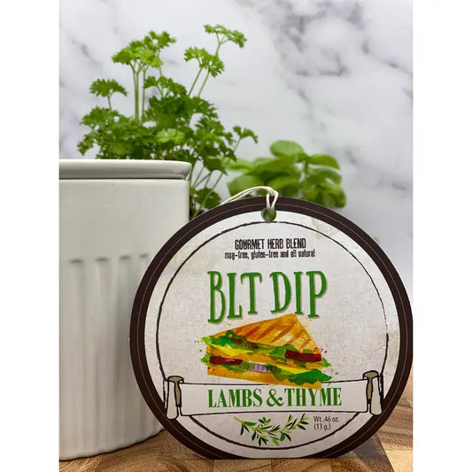 Round container of BLT Dip by Lambs & Thyme with a plant in the background