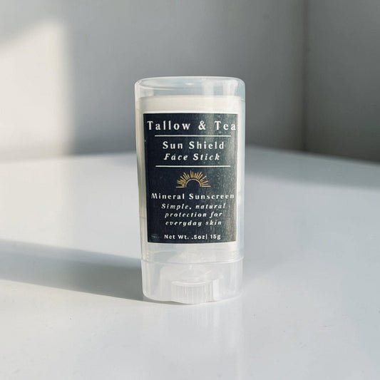 Tallow & Tea Sun Shield Face Stick on a light surface with a gray background