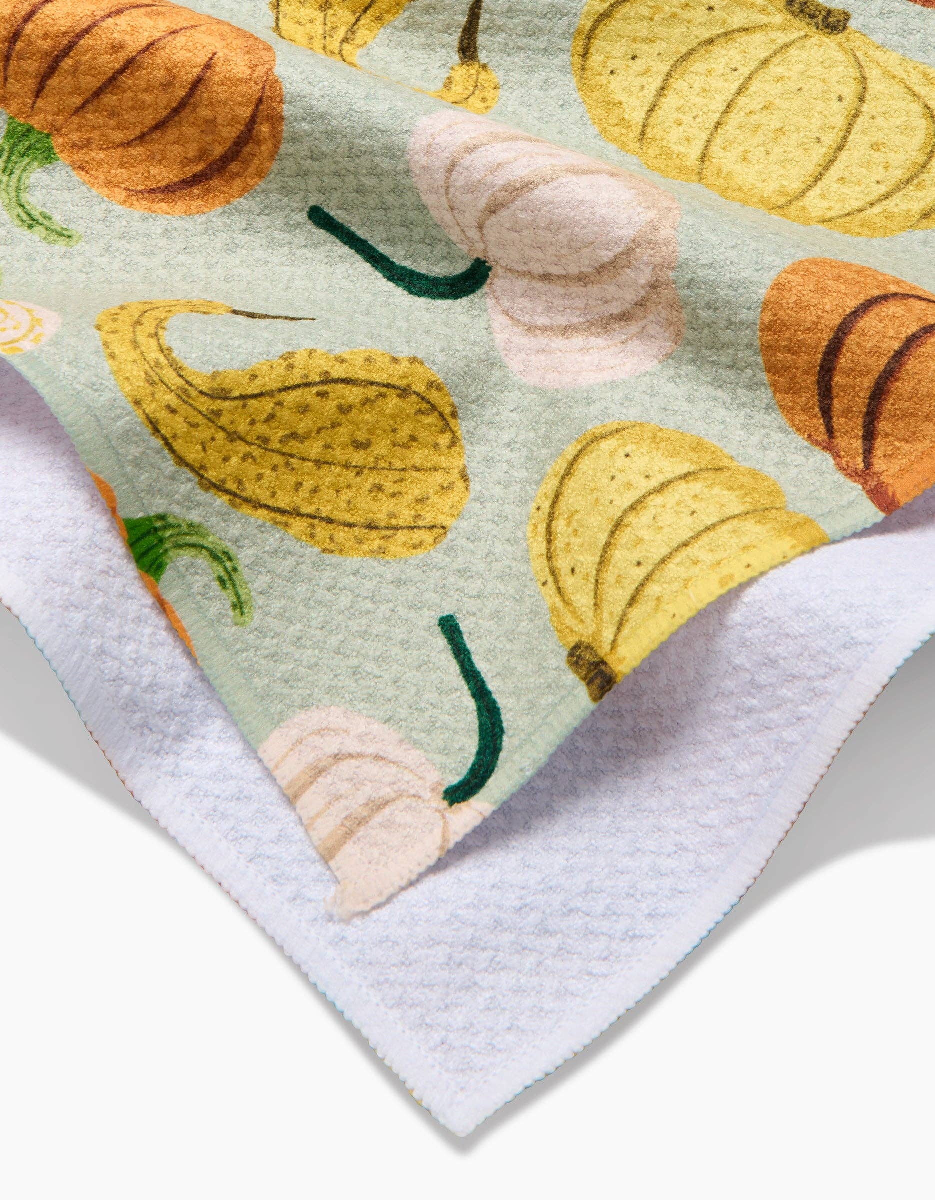 Close-up of a rug with pumpkins and gourds pattern on a light green background.
