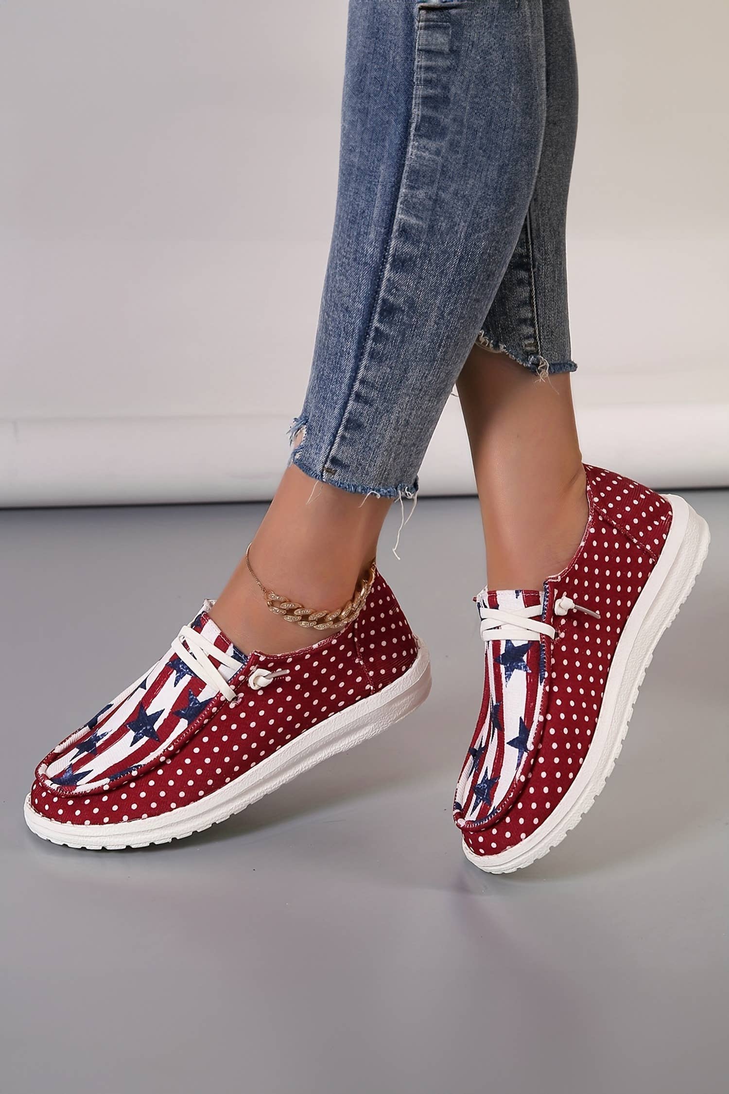 Red polka dot shoes worn with blue jeans on a neutral background