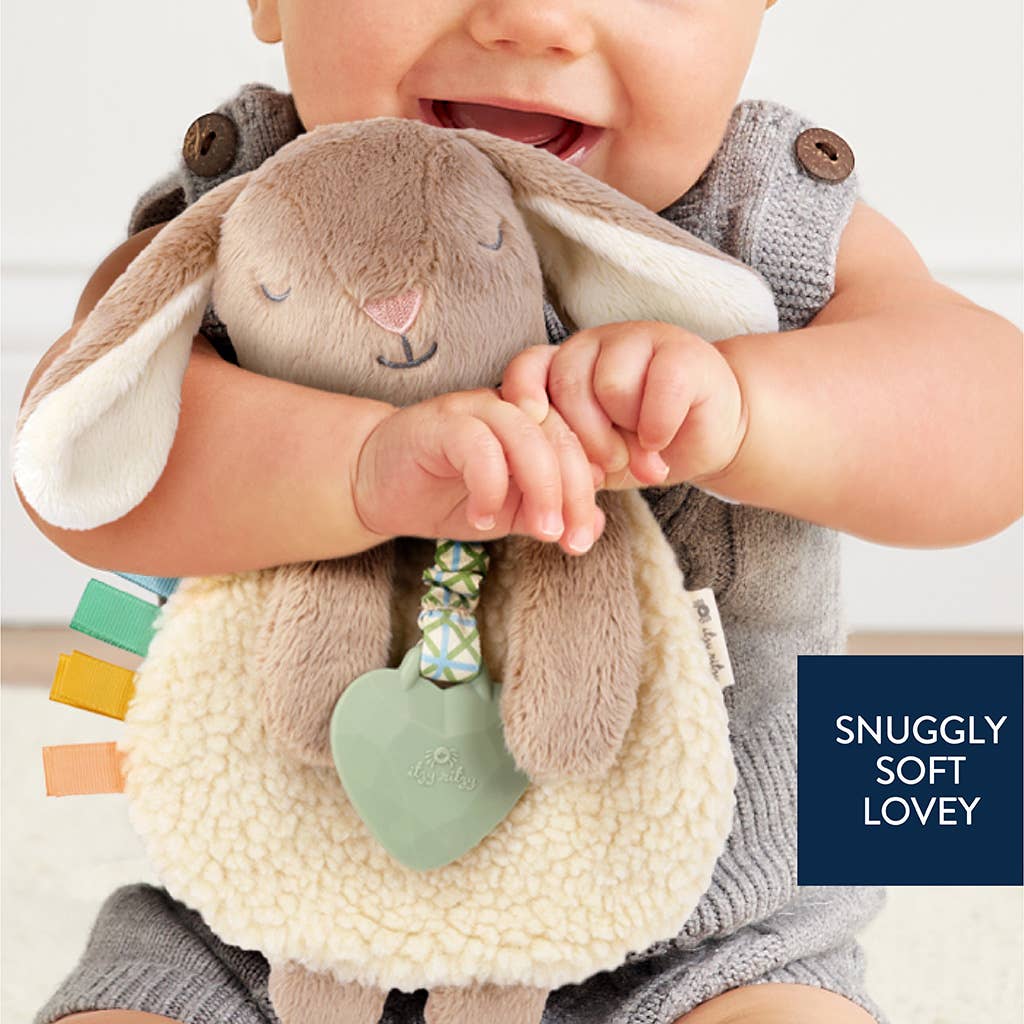 Child holding a soft toy with text 'Snuggly Soft Lovey' on a blurred background