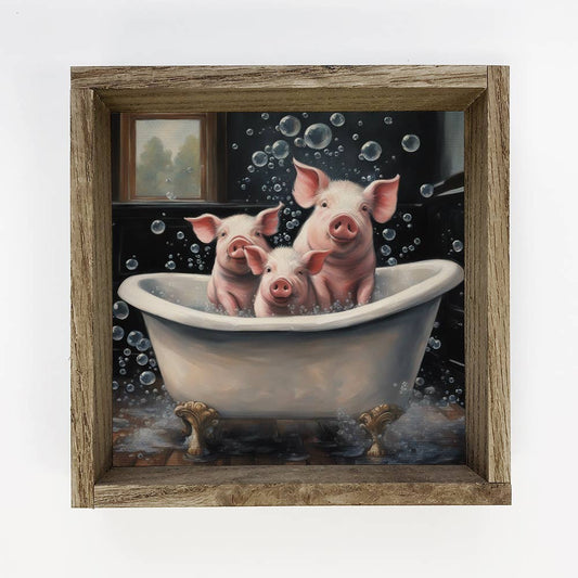 Three pigs in a bathtub with bubbles, framed by a wooden border.