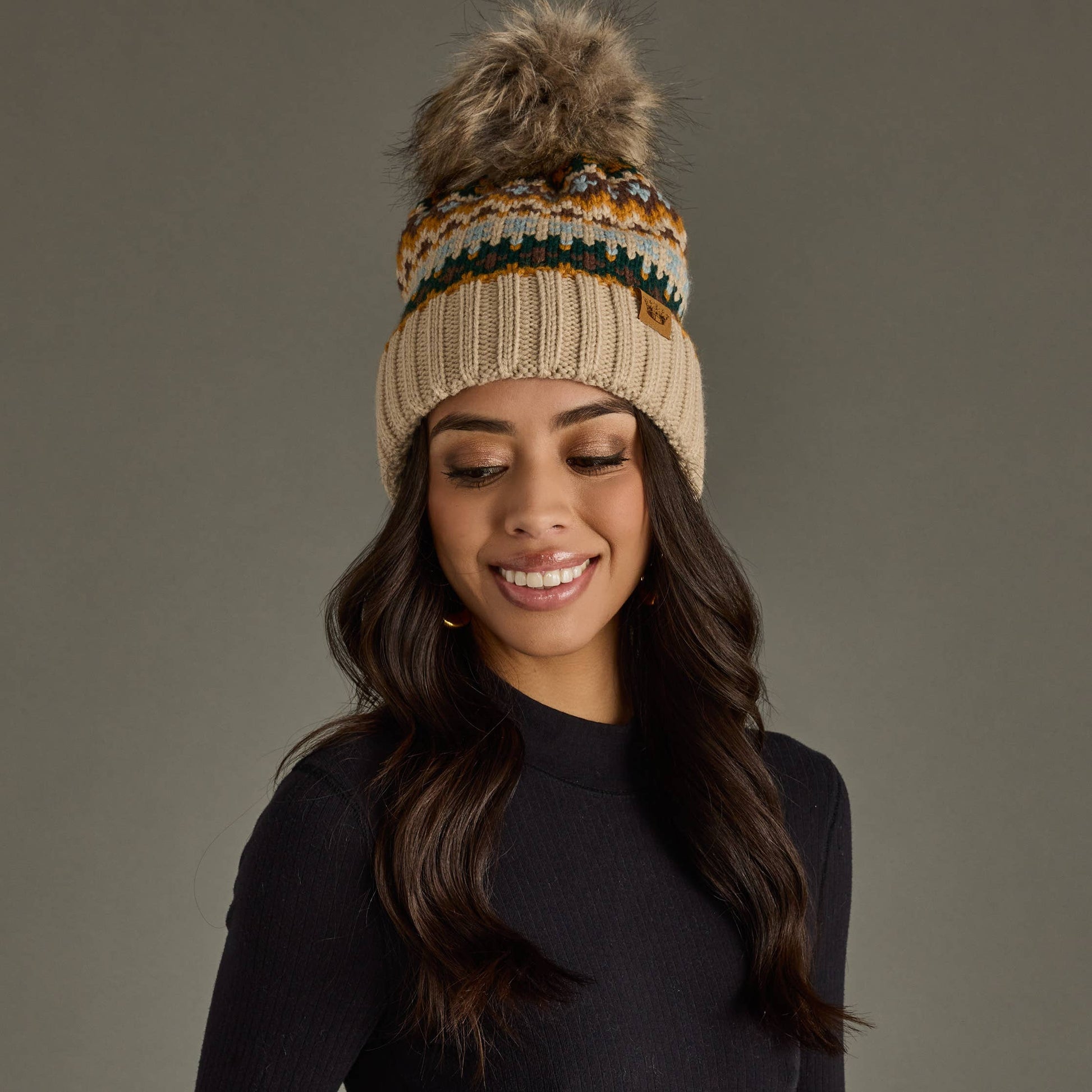 Woman wearing a patterned knit beanie with a pom-pom on a gray background