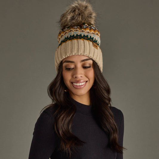 Woman wearing a patterned knit beanie with a pom-pom on a gray background