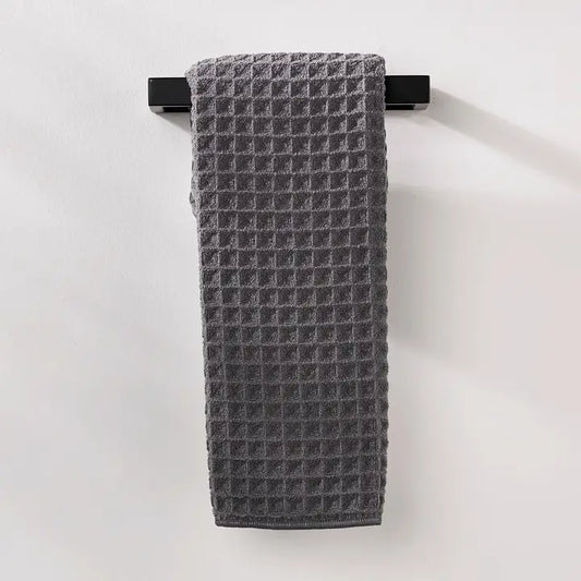 Gray textured Geometry Waffle hand towel hanging on a black rack against a white background