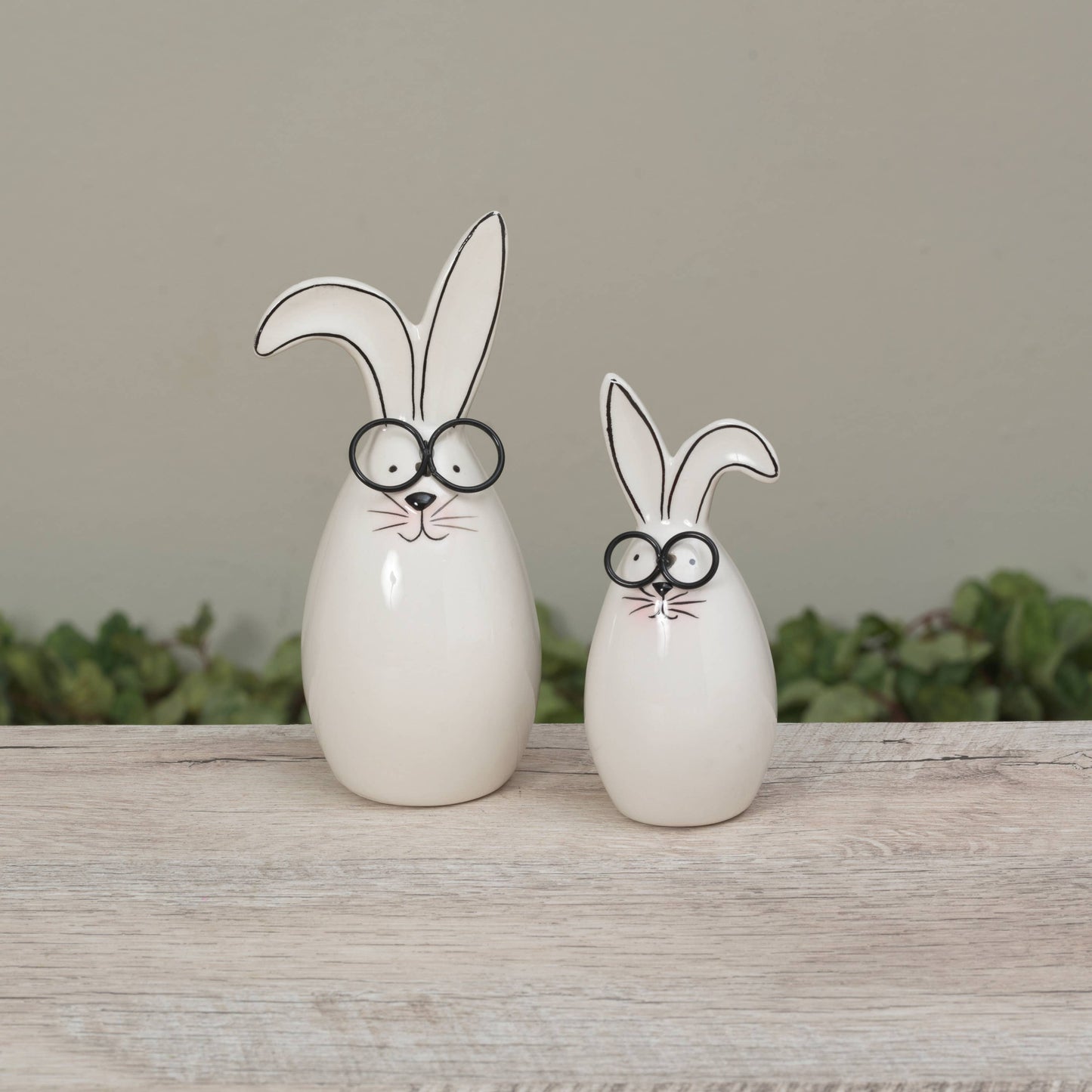 Two ceramic rabbit figures with googly eyes on a wooden surface.